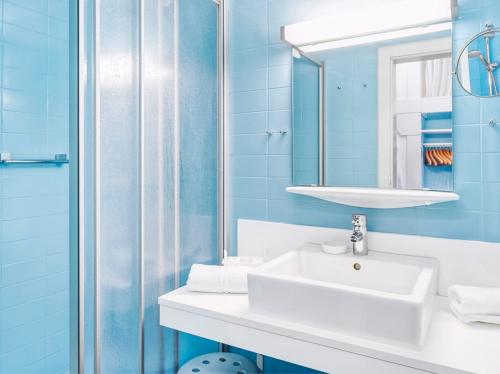 a blue bathroom with a sink and a mirror at Genuss - und Vitalhotel Moisl in Abtenau
