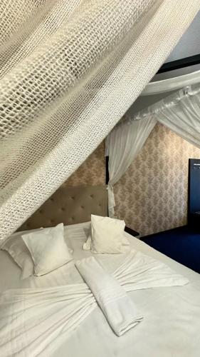 a bed with white sheets and pillows on it at Doftana Nature Events in Trăisteni