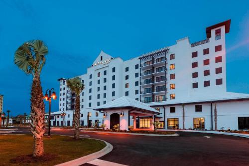 a large white hotel with a palm tree and a street at SpringHill Suites by Marriott Navarre Beach in Navarre