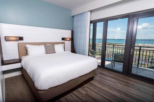 a bedroom with a bed and a balcony at SpringHill Suites by Marriott Navarre Beach in Navarre