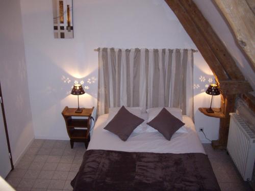 a bedroom with a bed with two pillows and a window at Auberge De La Luzerne in Bernières-sur-Mer