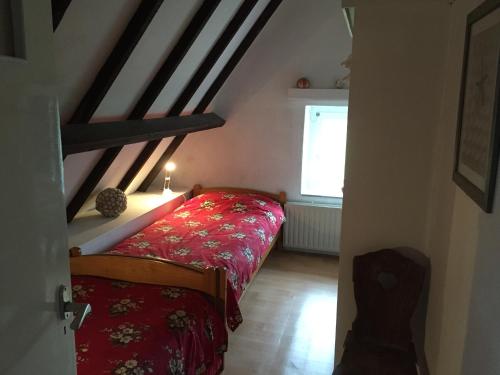 ein Schlafzimmer mit einem roten Bett im Dachgeschoss in der Unterkunft Villa Sint Anna in Sint Anna ter Muiden
