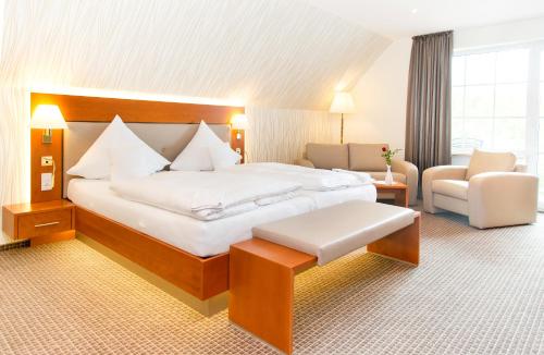 a hotel room with a large bed and a chair at Ringhotel Teutoburger Wald in Tecklenburg