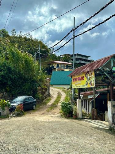 a car parked next to a building with a sign at Kanso Hill Guesthouse in Ranau
