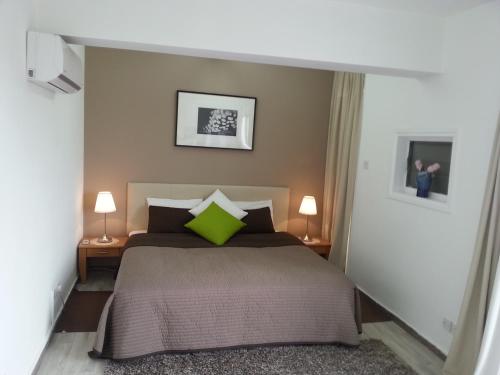 a bedroom with a bed with a green pillow at DownTown Living By 'Flats Nicosia' in Nicosia