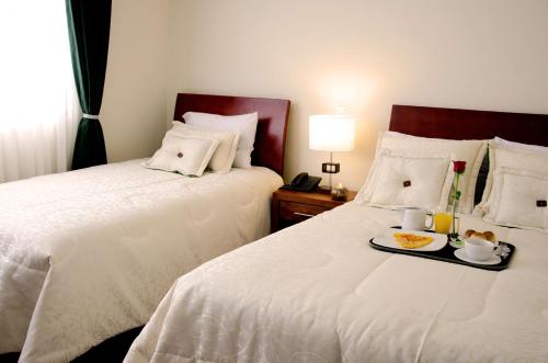 a hotel room with two beds with a tray of food at Hotel Portofino in Bogotá