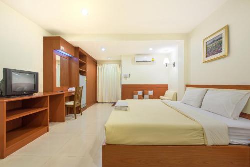 a bedroom with a bed and a desk with a television at Nuntiya Terrace in Udon Thani