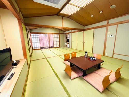 a room with a table and chairs and a television at Hotel Takasago in Kochi