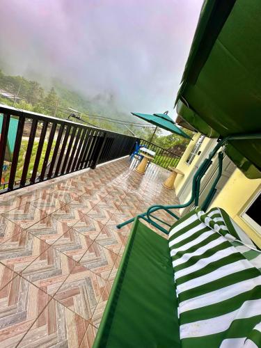 a balcony with a green bench on a deck at Kanso Hill Guesthouse in Ranau