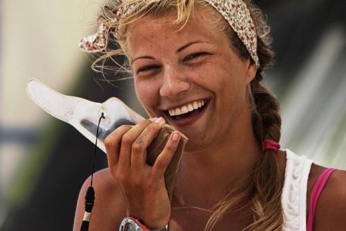 a woman is laughing while talking on a hair dryer at Prasonisi Club in Kattavía