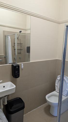 a bathroom with a toilet and a sink and a mirror at Bat and Ball Hostel in Sydney