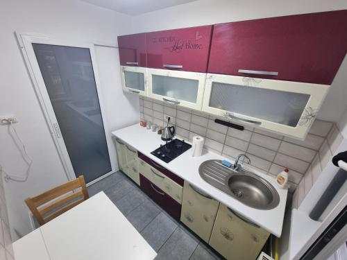 ピアトラ・ネアムツにあるFeel Like Home 2の小さなキッチン(シンク、赤いキャビネット付)