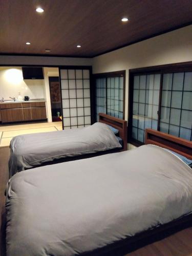 two beds in a room with windows and a kitchen at Daihachi in Takayama