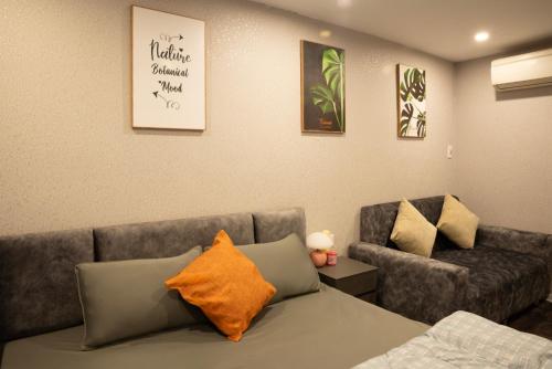 a room with a couch and a bed with an orange pillow at Spring Home Hà Nội in Hanoi
