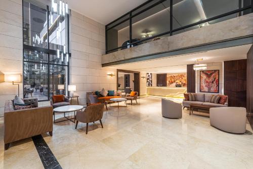 a lobby of a building with couches and tables at Doubletree By Hilton Amman Hotel & Residences in Amman
