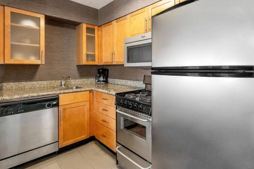 a kitchen with a stainless steel refrigerator and wooden cabinets at Residence Inn Denver North/Westminster in Westminster