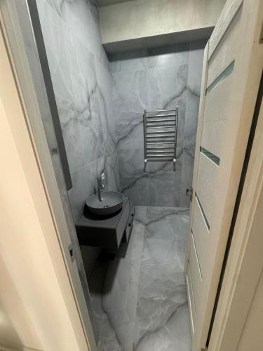 a bathroom with a sink and a white marble wall at Two bedroom MEGA MALL Hills Sports & Spa adjacent120Meter13Ff in Yerevan