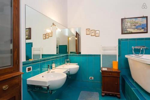 a blue bathroom with three sinks and a large mirror at Bed and Breakfast Adelberga in Salerno