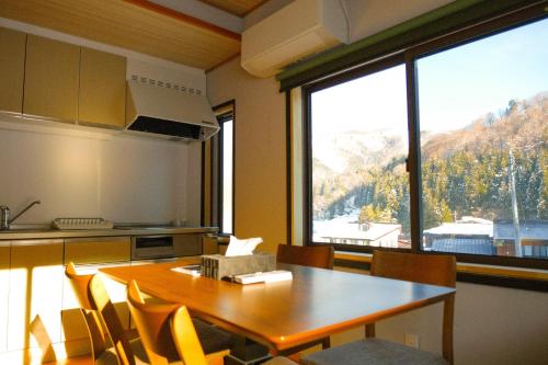 a kitchen with a table and chairs and a large window at Schanze Nozawa in Nozawa Onsen