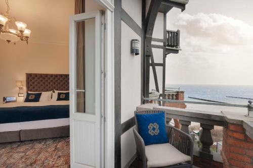a room with a bed and a balcony with the ocean at meergut HOTELS in Kühlungsborn