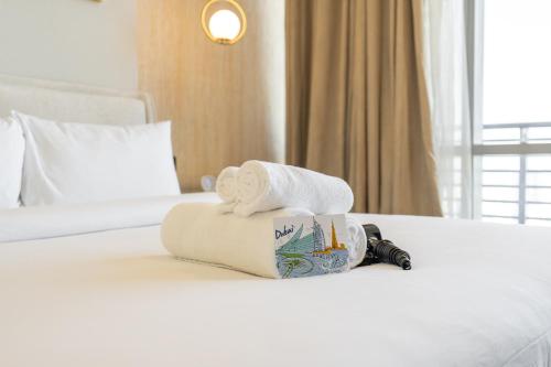 a hotel room with two towels and a cup on a bed at Studio in DIFC that Sleeps 4 Comfortably in Dubai