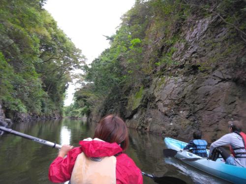 a woman is paddling a canoe down a river at 湖上館パムコ in Wakasa