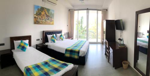 a hotel room with two beds and a balcony at The Cloud Hanthana, Kandy in Kandy