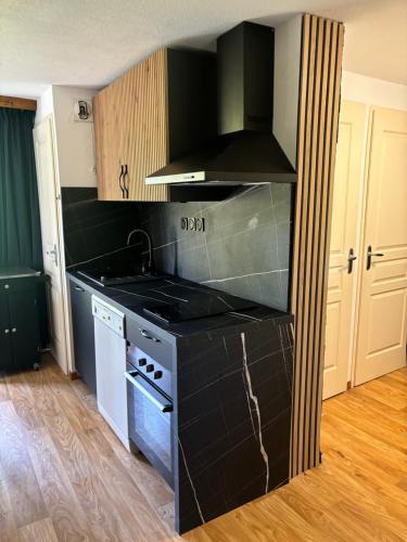 - une cuisine équipée de comptoirs noirs et d'une cuisinière four supérieur dans l'établissement La Parenthèse Chamroussienne - Proche pistes de ski, à Chamrousse