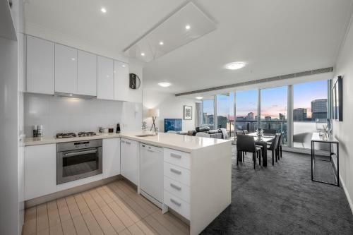 a kitchen with white cabinets and a dining room at Exclusive Stays - Vue Grande in Melbourne