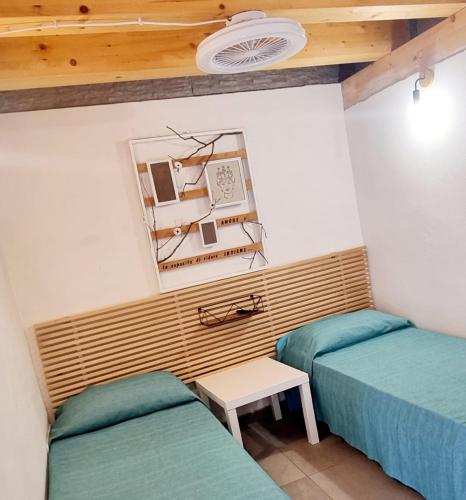 a room with two beds and a table and a mirror at Casa vacanza in lipari ,PIANO PIANO in Lipari