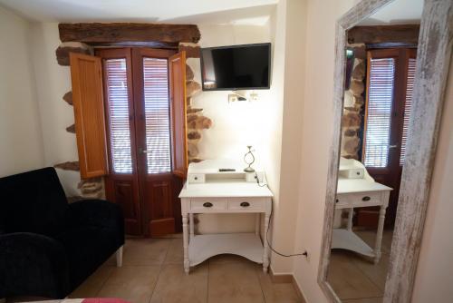 a living room with a table and a tv on a wall at Hotel Rural L'Antic Portal in Vilafames