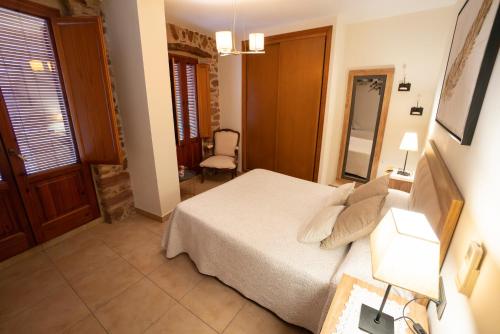 a bedroom with a bed and a chair and a mirror at Hotel Rural L'Antic Portal in Vilafames