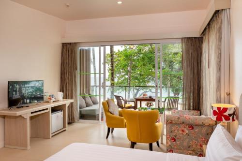 a living room with a large window and yellow chairs at The Briza Beach Resort, Khao Lak SHA Extra Plus in Khao Lak