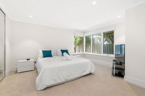a white bedroom with a large bed and a window at Exquisite Oasis Family Retreat in Perth
