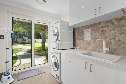 a kitchen with a washer and dryer next to a window at Exquisite Oasis Family Retreat in Perth