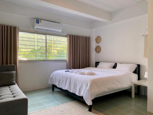 a bedroom with a large white bed and a window at Baiyok House in Ban Ai Dao