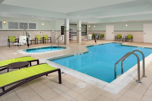 une piscine dans une chambre d'hôtel avec tables et chaises dans l'établissement SpringHill Suites Alexandria, à Alexandria