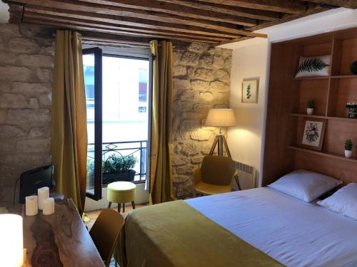 une chambre avec un lit et une grande fenêtre dans l'établissement Coup de cœur à Montorgueil, à Paris