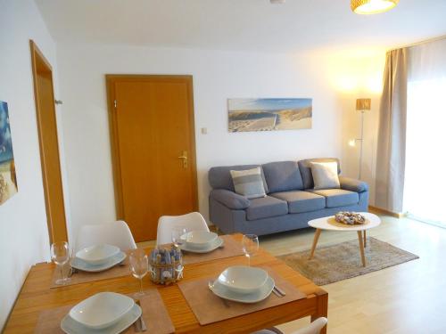 a living room with a table and a blue couch at Ferienwohnungen mit "Strandfeeling" Waldstraße 15 Kellenhusen Ostsee in Kellenhusen