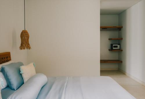 a white bed with blue pillows in a bedroom at Marlaca Villas Lombok in Kuta Lombok