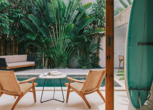 a patio with two chairs and a table and a surfboard at Marlaca Villas Lombok in Kuta Lombok