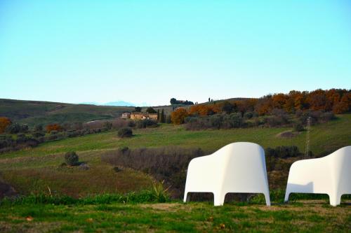 two white chairs sitting on top of a field at Podere Campiano in Volterra