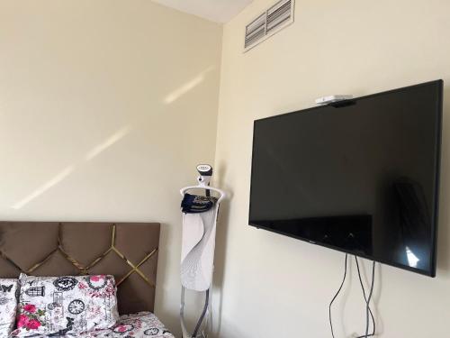 a flat screen tv hanging on a wall next to a bed at SHJ DXB Sunny Border Guesthouse in Dubai