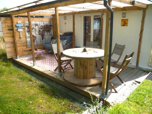 a patio with a table and chairs on a deck at Cocon des marais in Bourgneuf-en-Retz