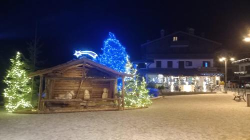 a group of christmas trees and a log cabin with blue lights at Colleoni Apartment di Manenti Andrea in Oltre il Colle