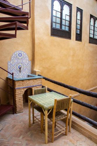 a table and chairs in a room with a table and a chair at Riad Hmam Sofa in Taroudant