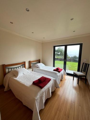 two beds in a room with a large window at Deluxe House in Angra do Heroísmo