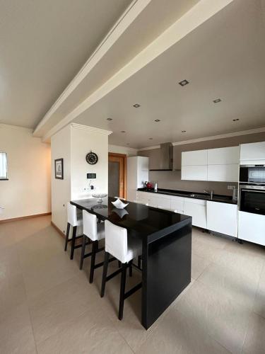a large kitchen with a black table and white cabinets at Deluxe House in Angra do Heroísmo