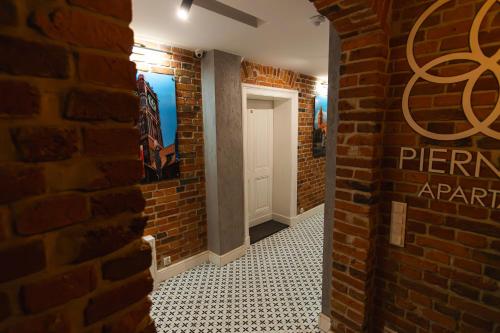 a hallway with a brick wall and a white door at Apartamenty Piernikowe Toruń Jacuzzi in Toruń