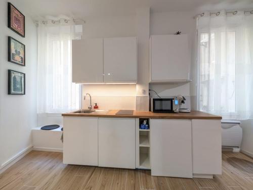 a kitchen with white cabinets and a counter with a microwave at Mourillon proche plages in Toulon